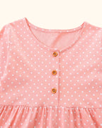 Pale blush kids polka dot dress with round neck and three-button placket, bodice close-up