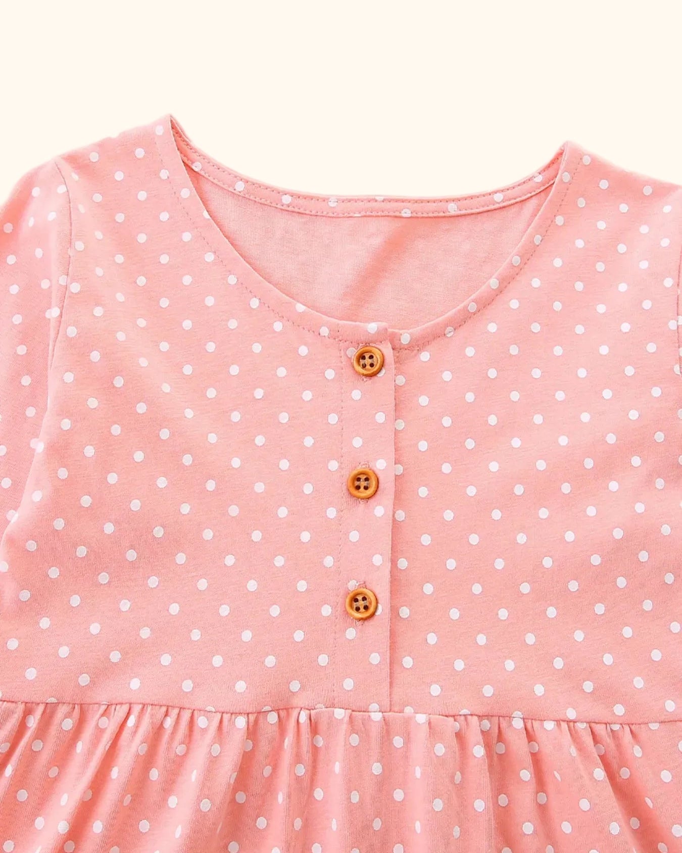 Pale blush kids polka dot dress with round neck and three-button placket, bodice close-up