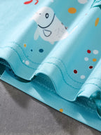 Pastel blue kids sea turtle print fabric with white fish and colorful ocean dots, hem detail view
