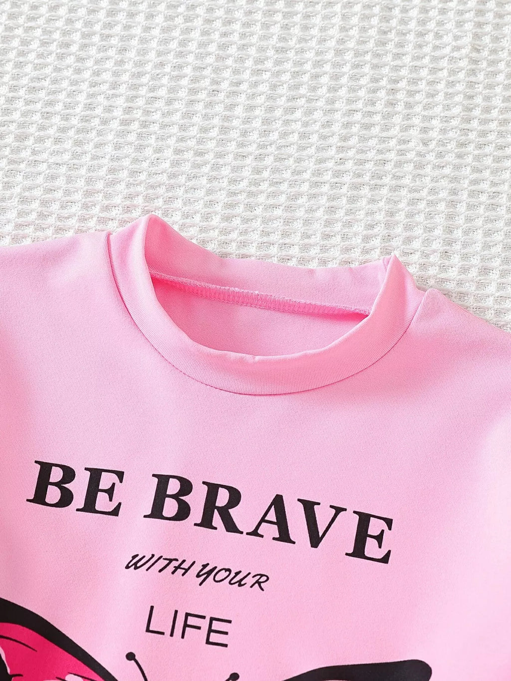 Pink butterfly graphic tee with embroidered detailing, front close-up