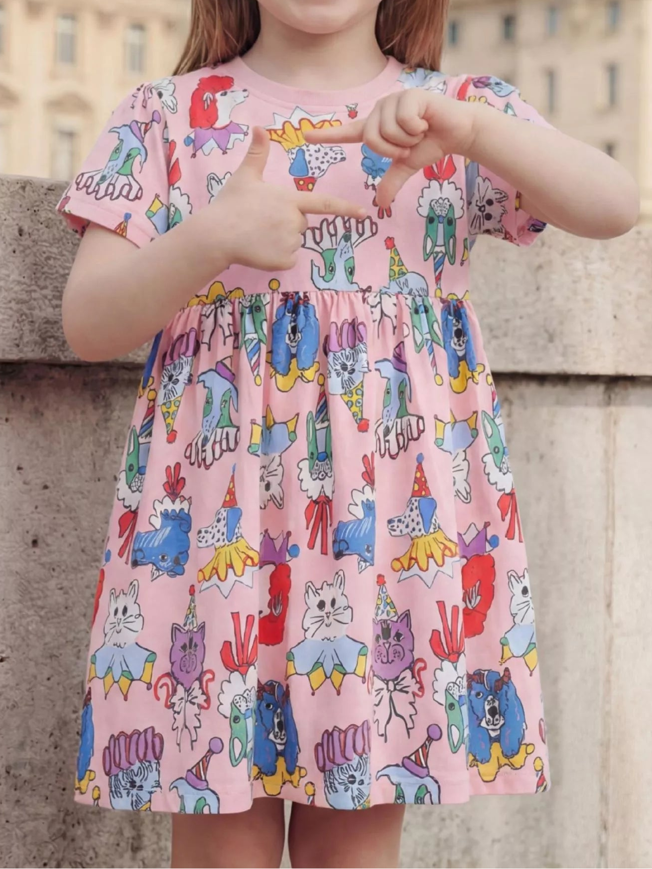 Pink kids cartoon animal print dress with playful cats and dogs, modeled front view