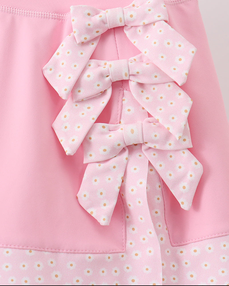 Pink kids skort with three stacked daisy-print bows, close-up detail view