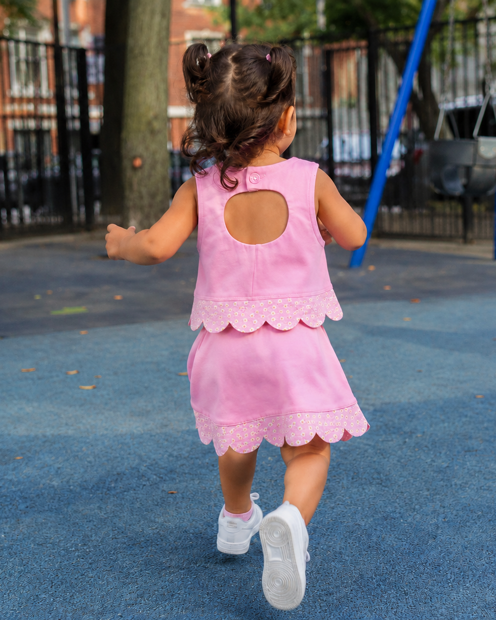 Pink kids daisy scalloped active top and skort set, rear playground lifestyle view