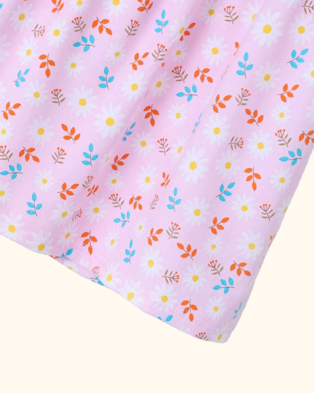 Pink kids dress with white daisy floral print and colorful leafy details, fabric close-up