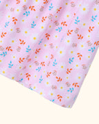 Pink kids dress with white daisy floral print and colorful leafy details, fabric close-up