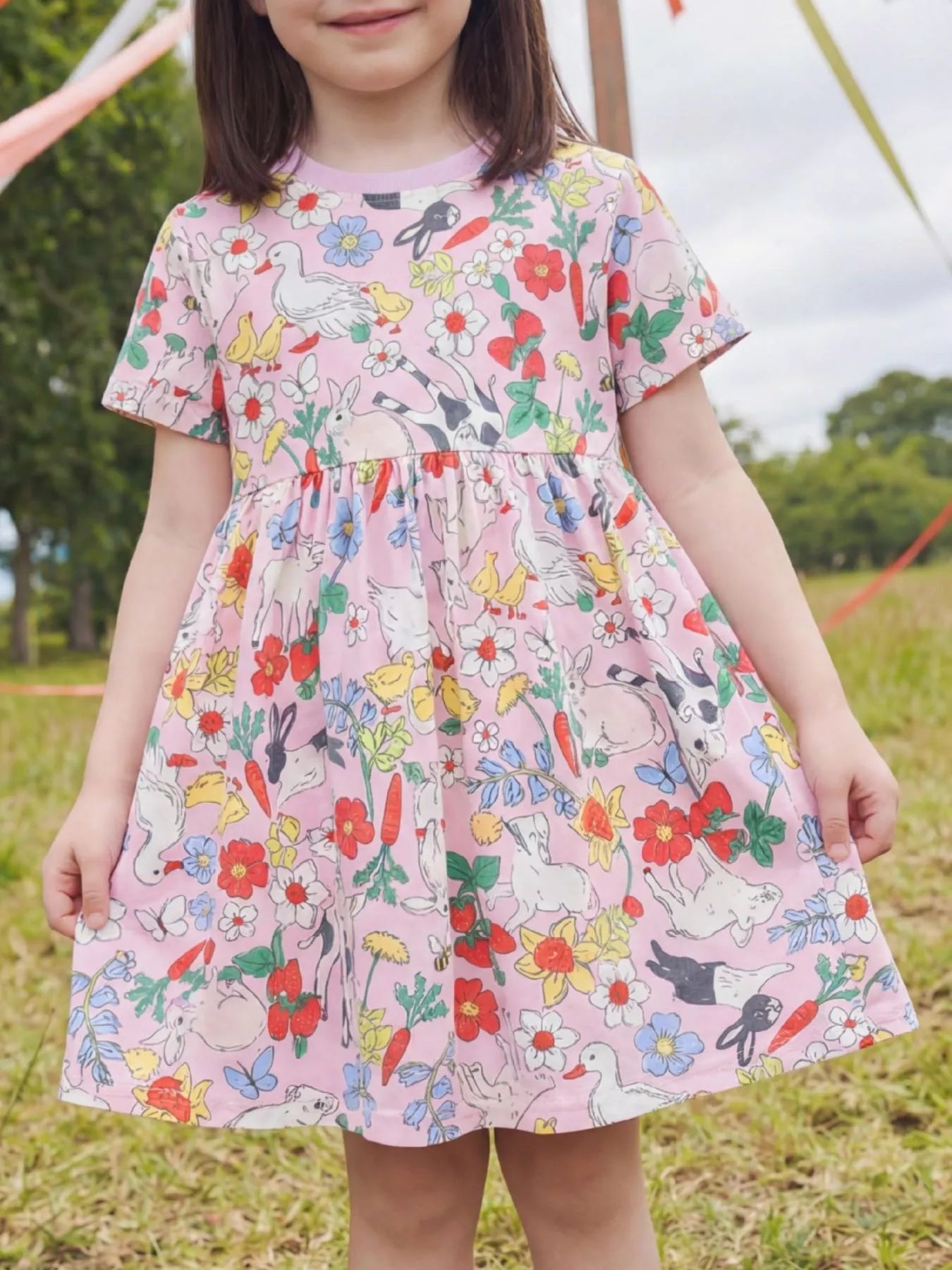 Pink kids garden animal print dress with gathered waist and full skirt, front lifestyle view