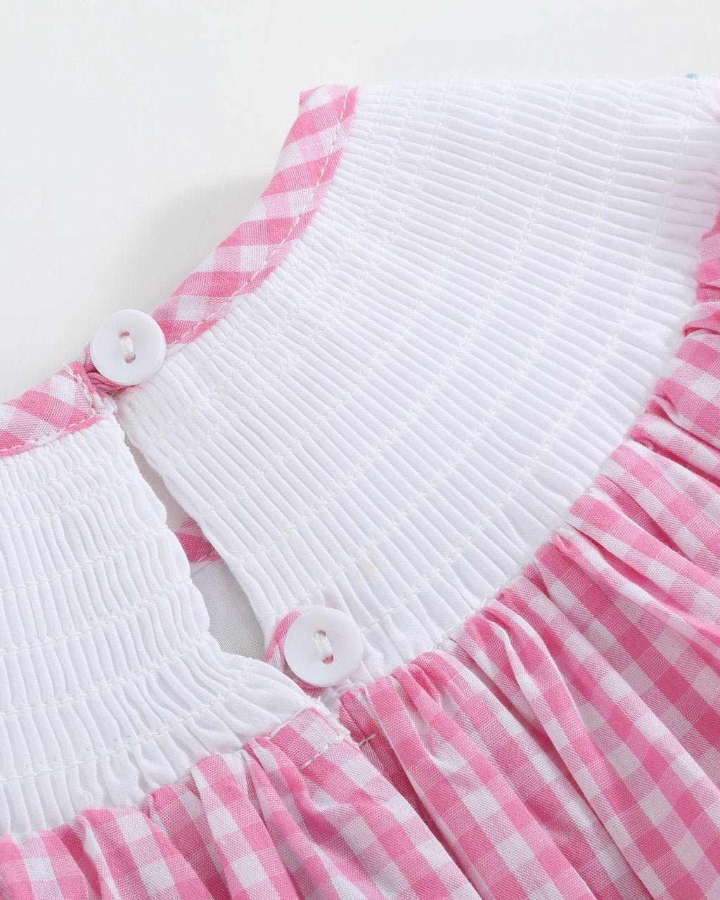Pink gingham ABC bishop dress with smocked neckline and ric-rac accents, angled view