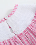 Pink gingham ABC bishop dress with smocked neckline and ric-rac accents, angled view