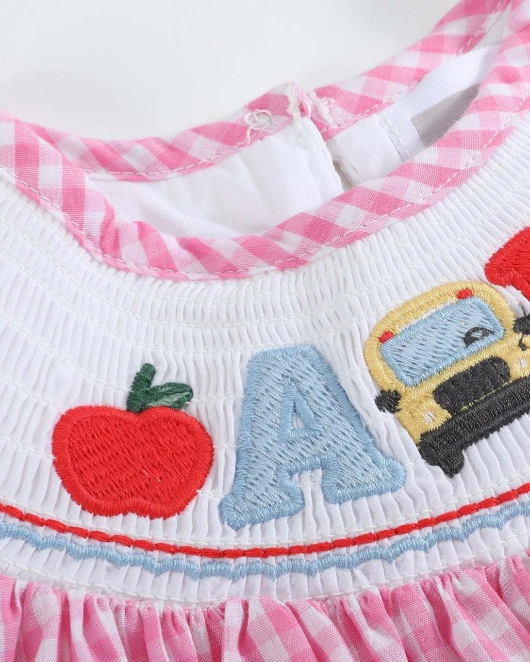 Pink gingham ABC school bishop dress with smocked embroidered neckline, front view