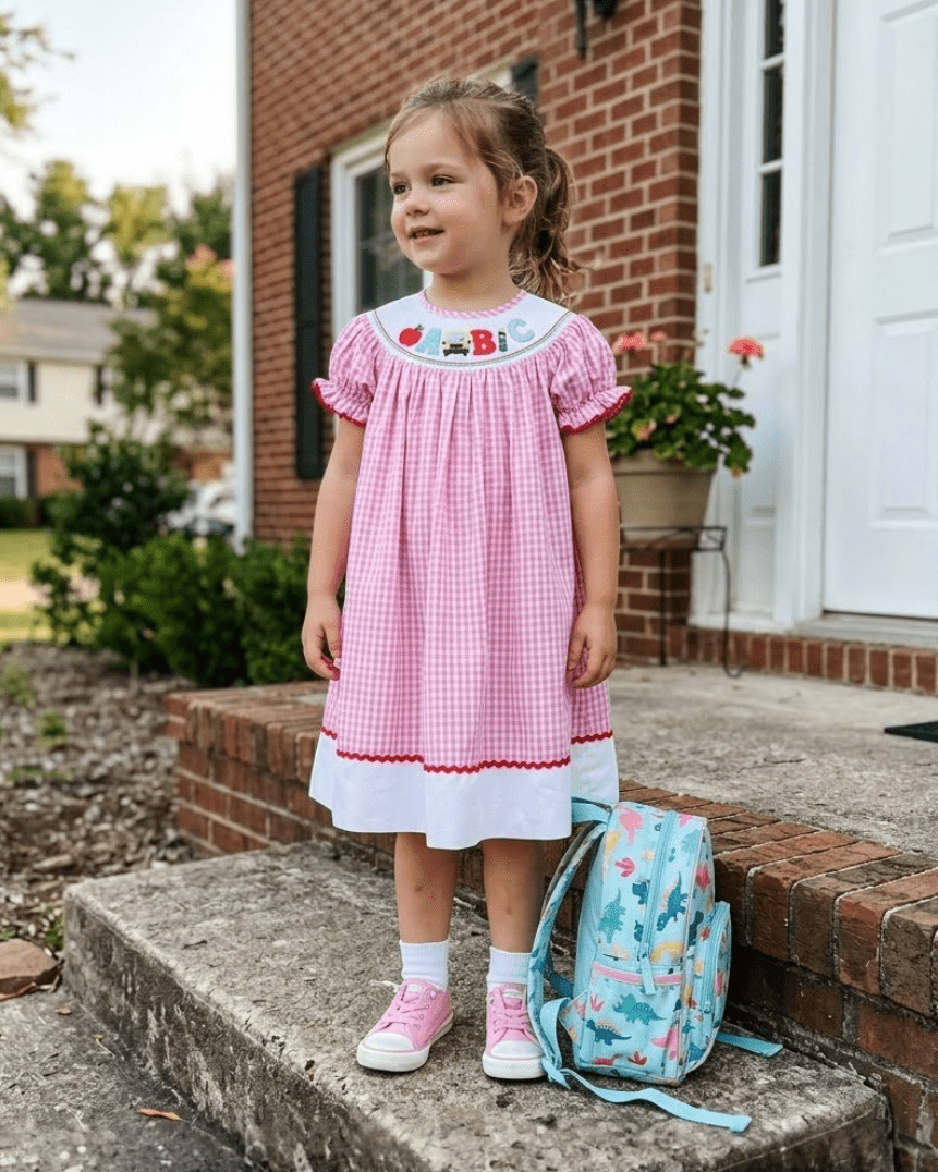 Pink gingham school bishop dress with full gathered silhouette, modeled front view