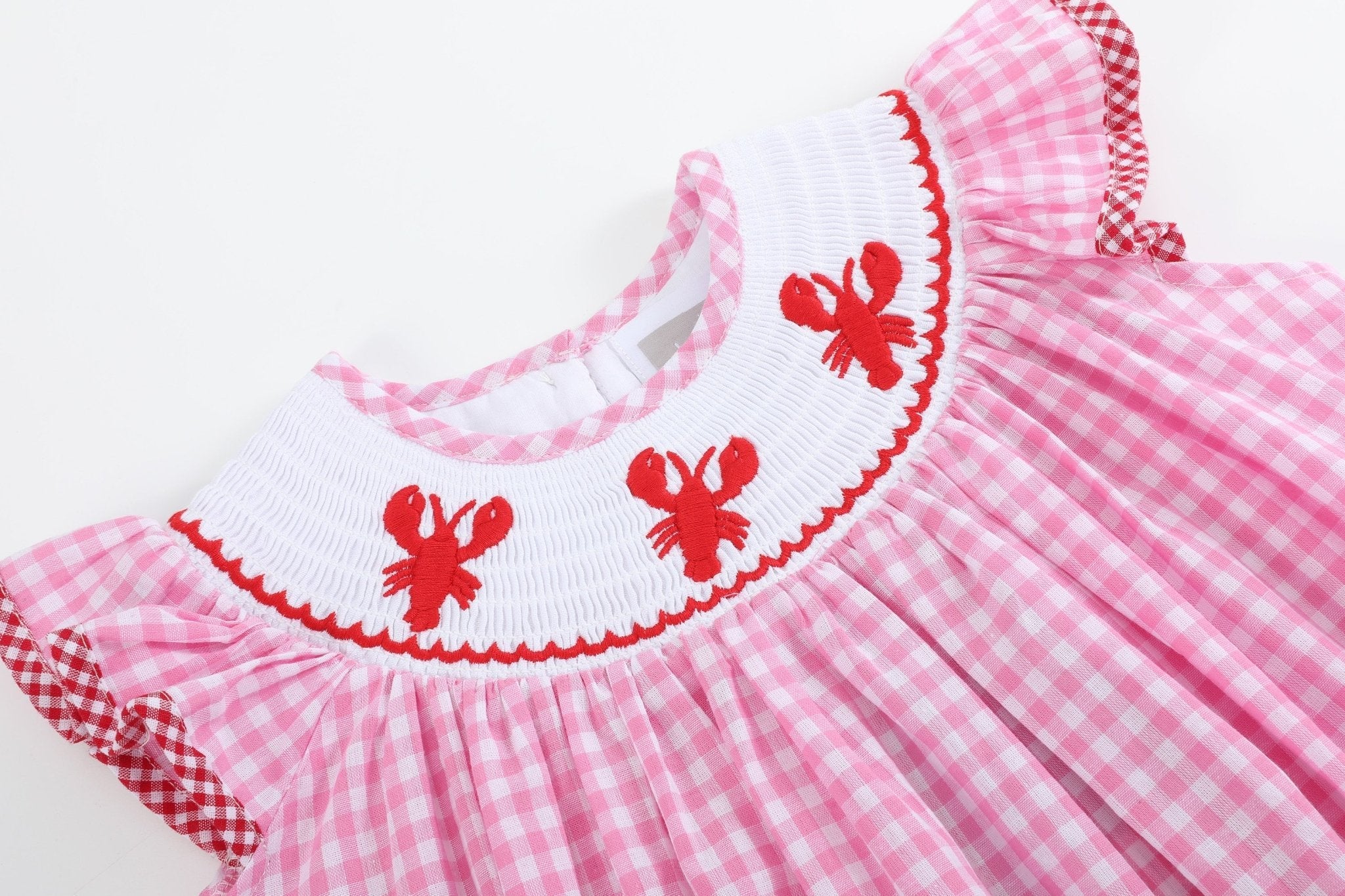 Pink gingham kids bishop dress with red crawfish embroidery and white smocked neckline, close-up