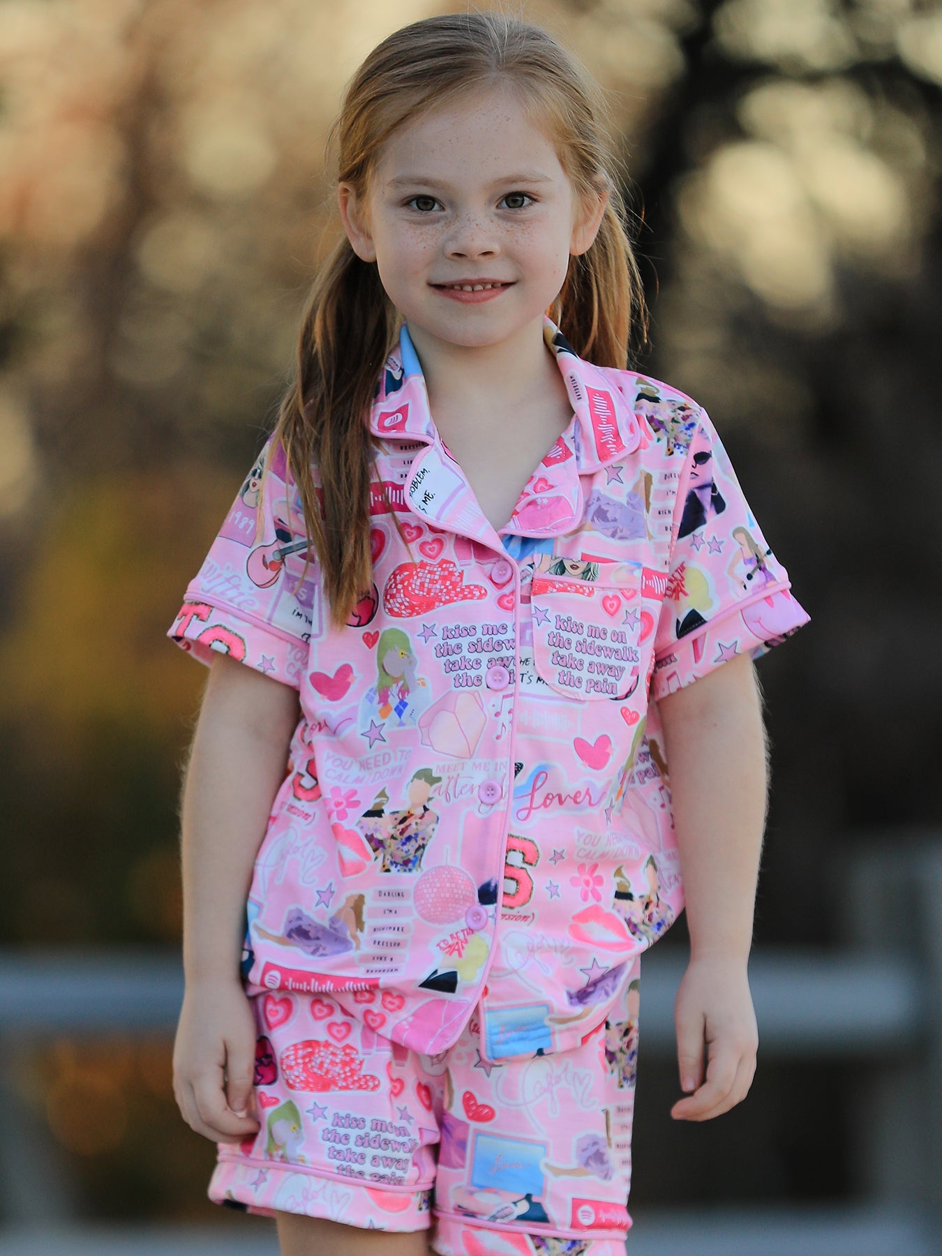 Pink kids button-up pajama top with notched collar, chest pocket and matching shorts, modeled front view