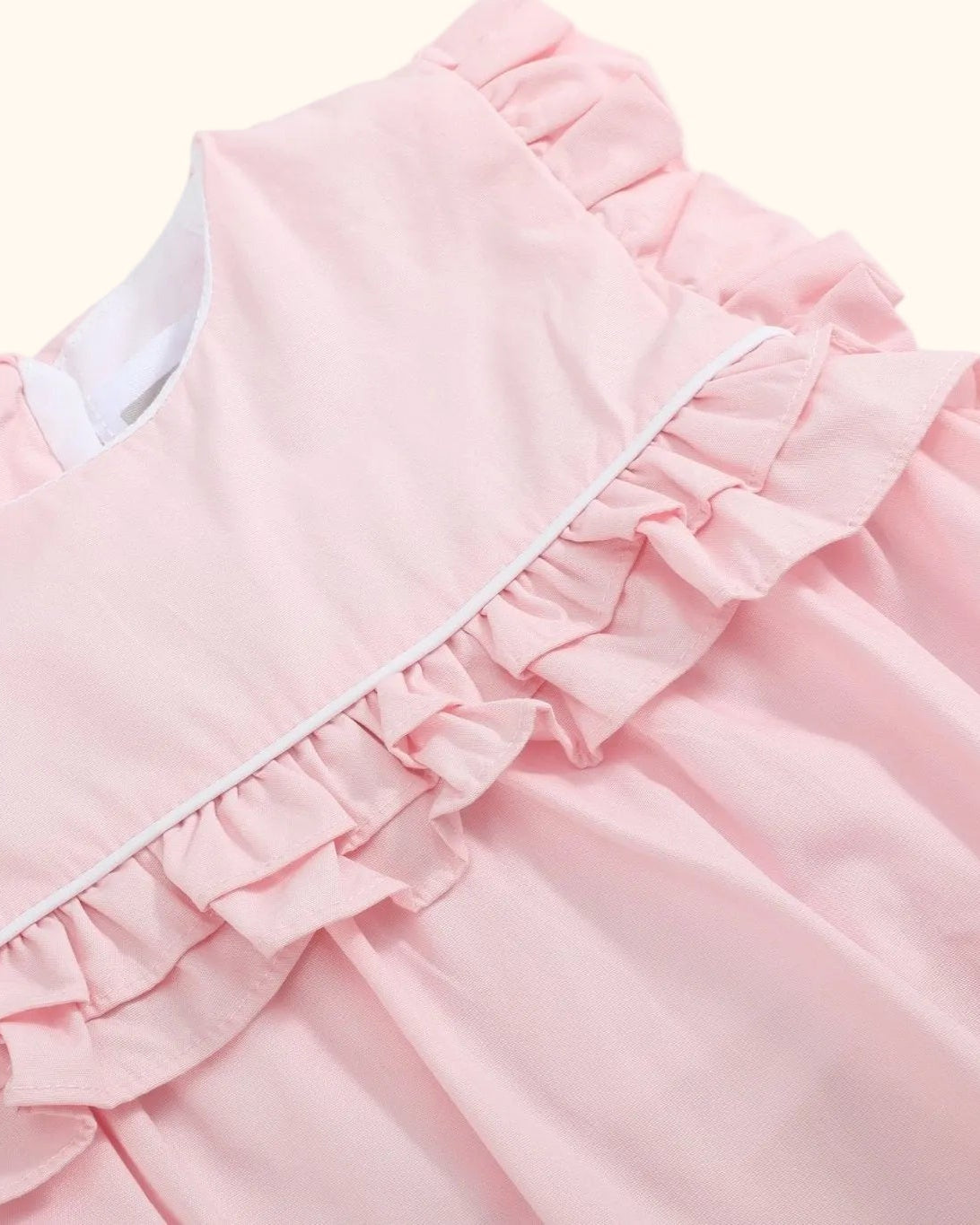 Pink baby jumper romper with layered ruffles and white piping, bodice close-up