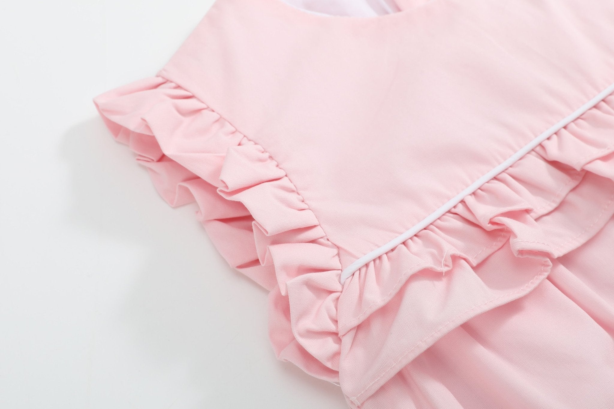 Pink baby jumper romper with ruffled shoulder and layered chest trim, detail view