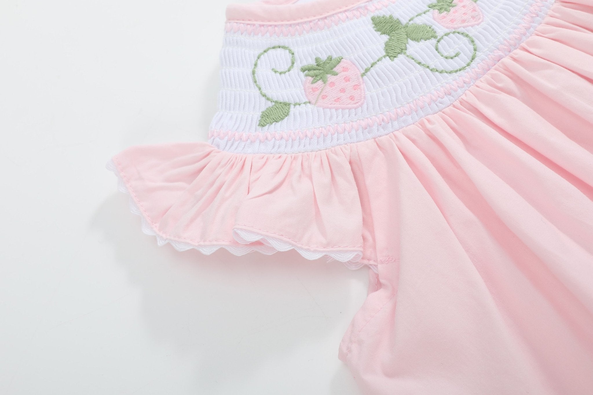 Pink strawberry smocked bishop dress with ruffle sleeve and scalloped white trim, detail view