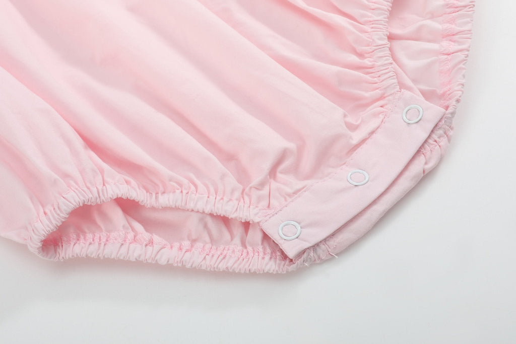 Pink baby bubble romper with elasticized leg openings and three bottom snaps, close-up view
