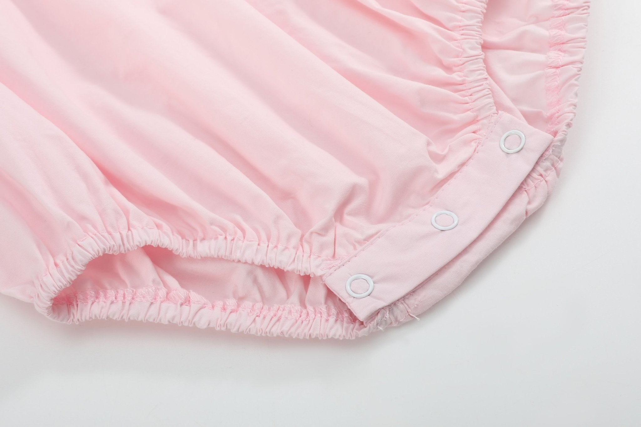 Pink baby bubble romper with elasticized leg openings and three bottom snaps, close-up view
