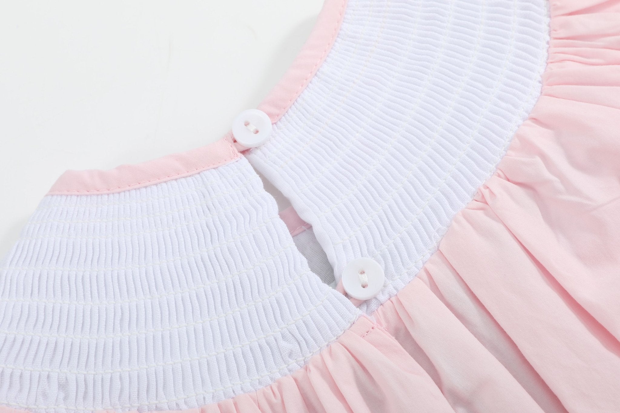 Pink baby smocked romper with two-button back neckline opening, close-up view