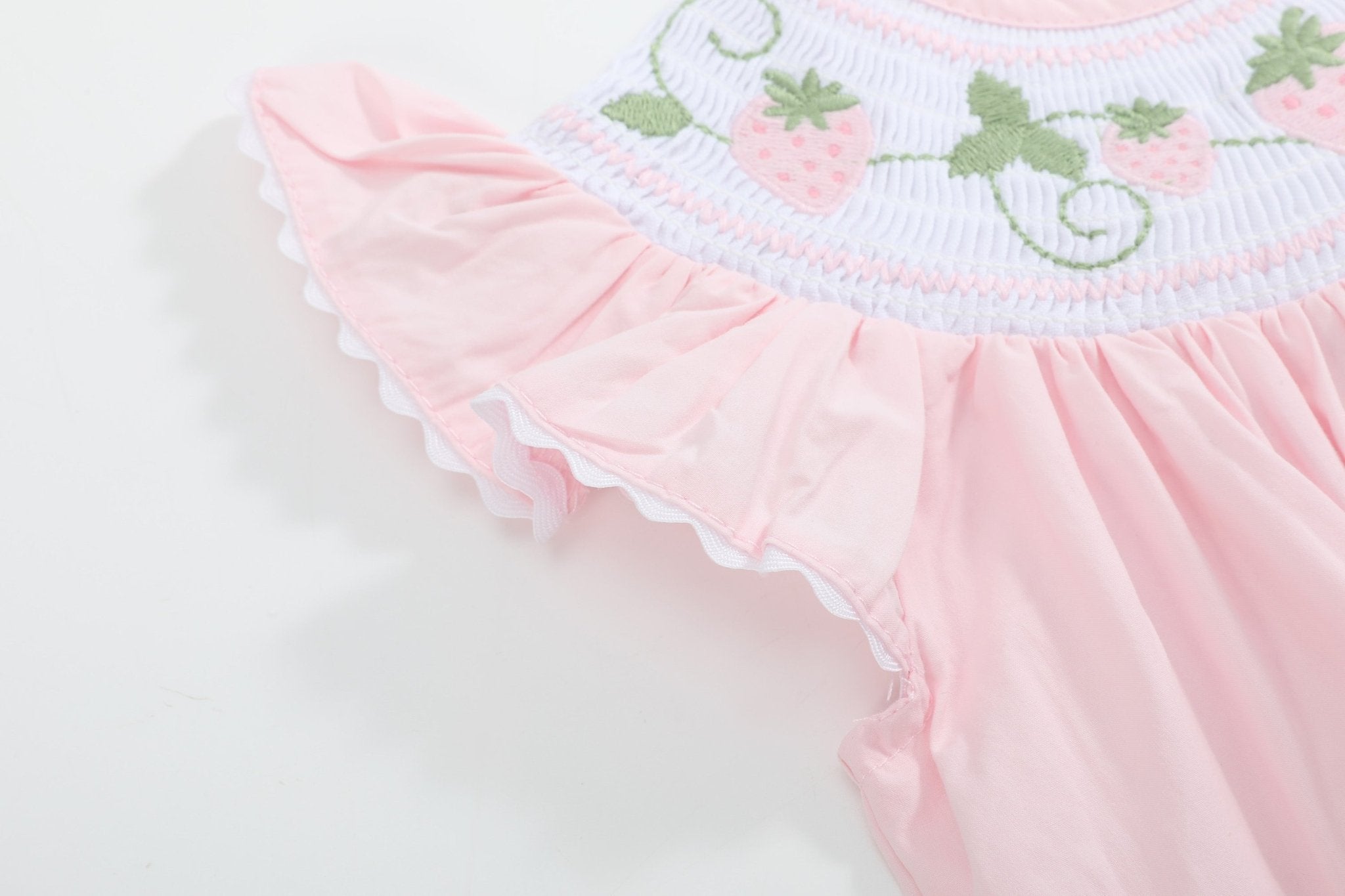 Pink baby strawberry romper with flutter sleeve and white scalloped trim, close-up view