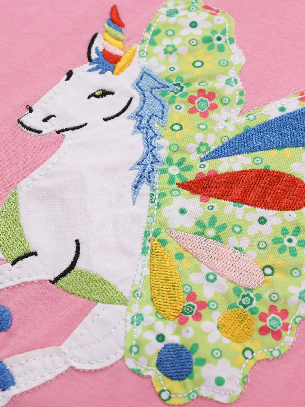 Pink kids T-shirt with white unicorn, floral wings and embroidered accents, design close-up