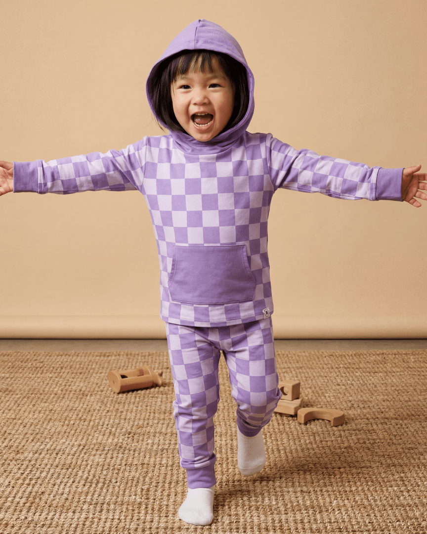 Purple checkerboard kids hooded jogger set with kangaroo pocket, modeled front action view