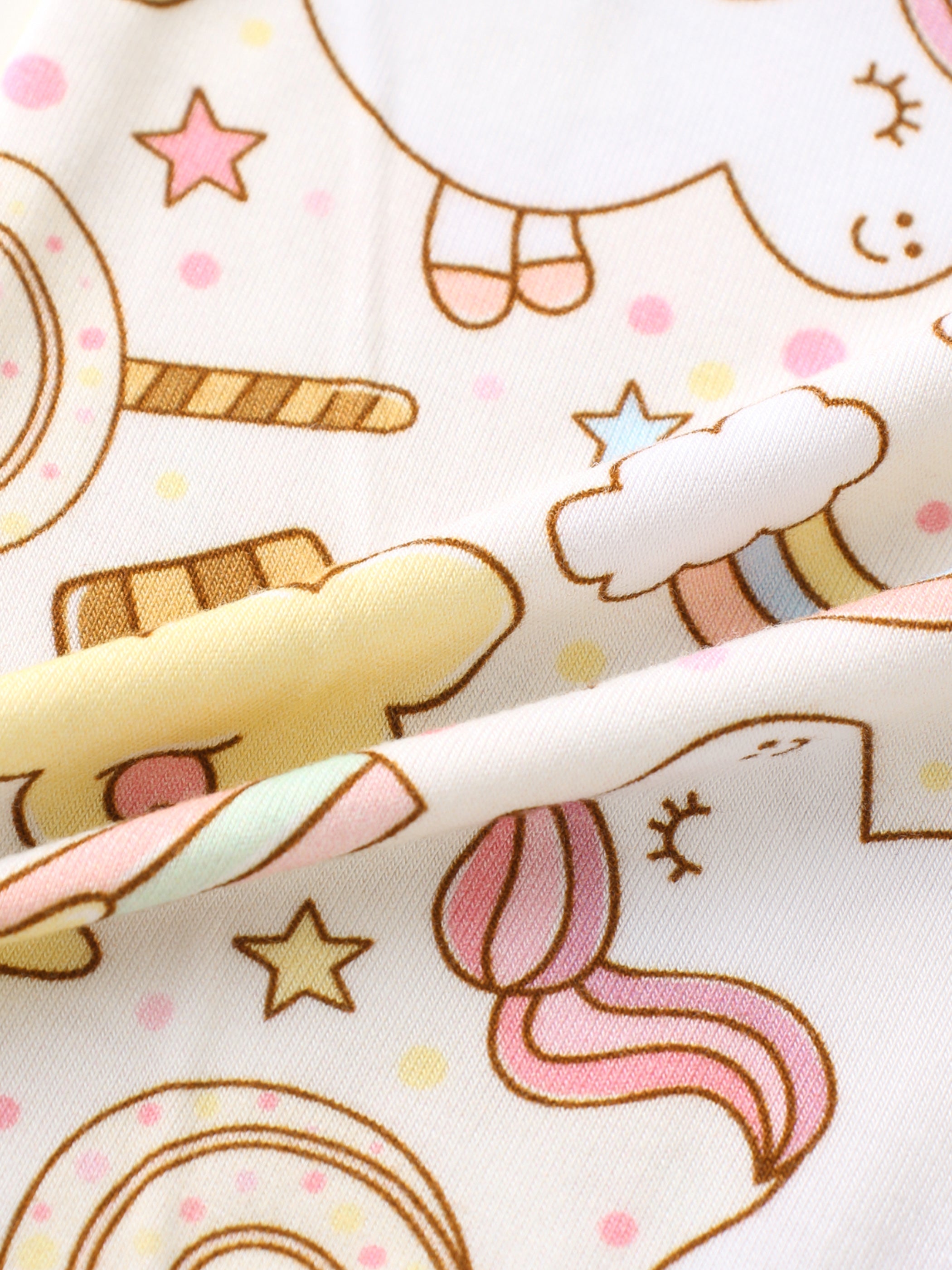 Cream bamboo romper fabric with unicorns, rainbows, lollipops and stars, print close-up
