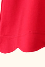 Red kids top with rounded scalloped bottom hem, close-up detail view