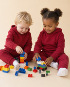 Rhubarb red kids hooded jogger set with matching pants, seated play lifestyle view