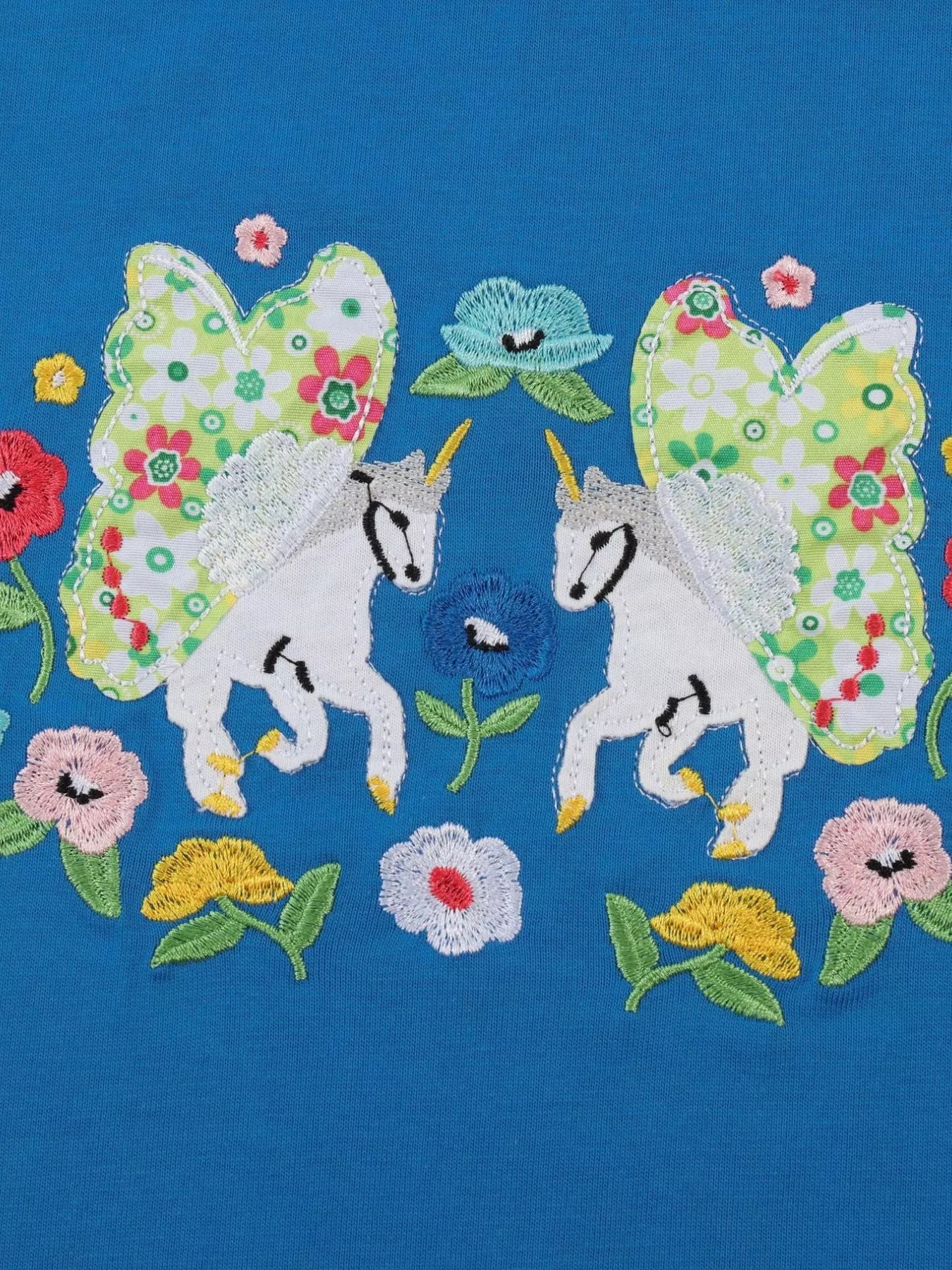 Royal blue kids T-shirt with two unicorn appliqués, floral wings and embroidered flowers, design close-up
