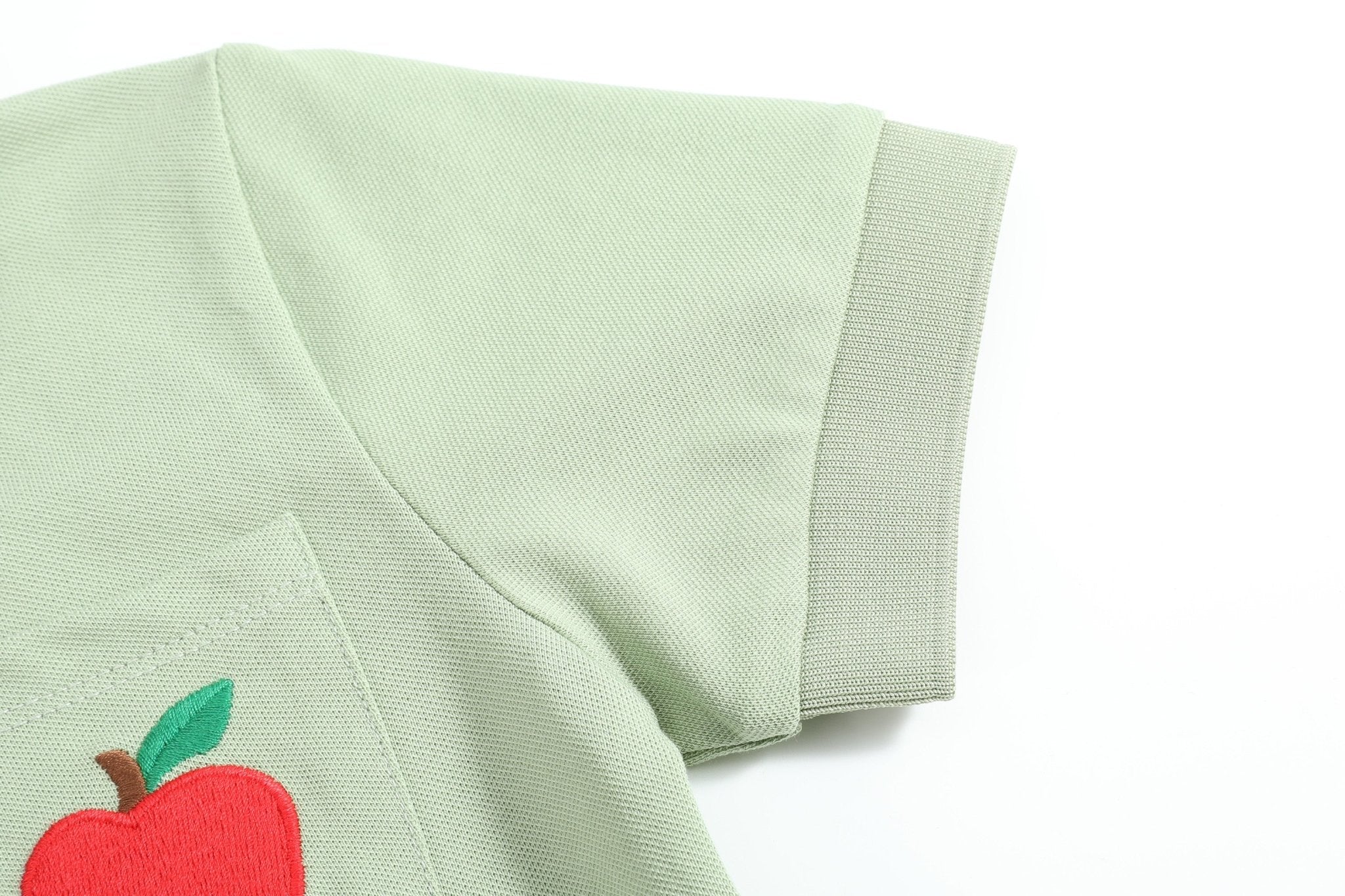 Sage green kids polo shirt with ribbed short-sleeve cuff and apple embroidery, sleeve detail view