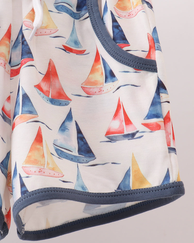 Colorful sailboat print kids shorts with blue contrast hem binding, close-up view