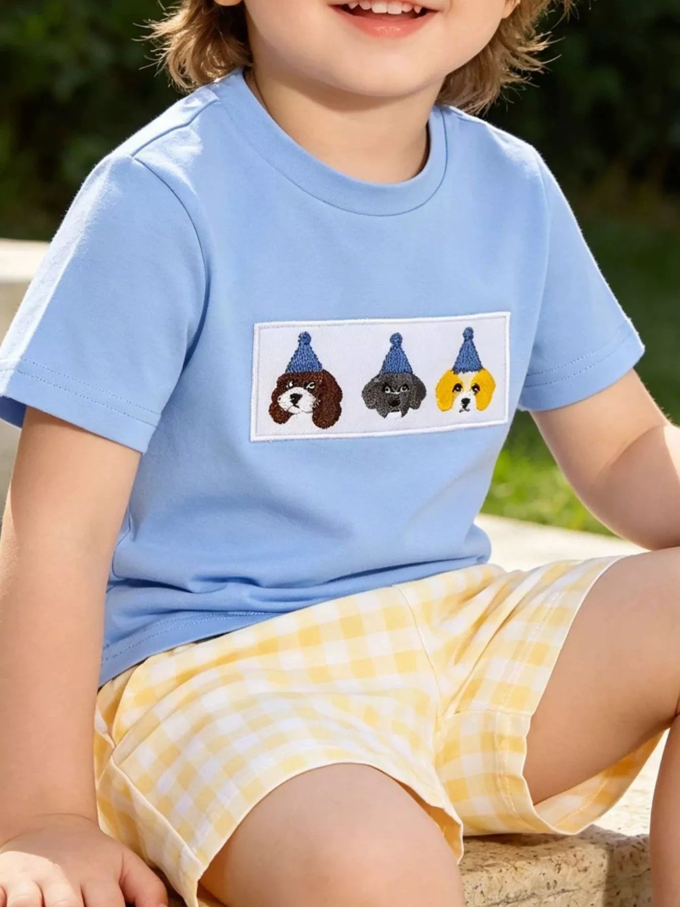 Sky blue baby puppy tee with embroidered three-dog chest patch and yellow gingham shorts, lifestyle view