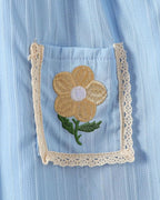Sky blue kids dress pocket with golden flower embroidery and cream lace edging, pocket close-up