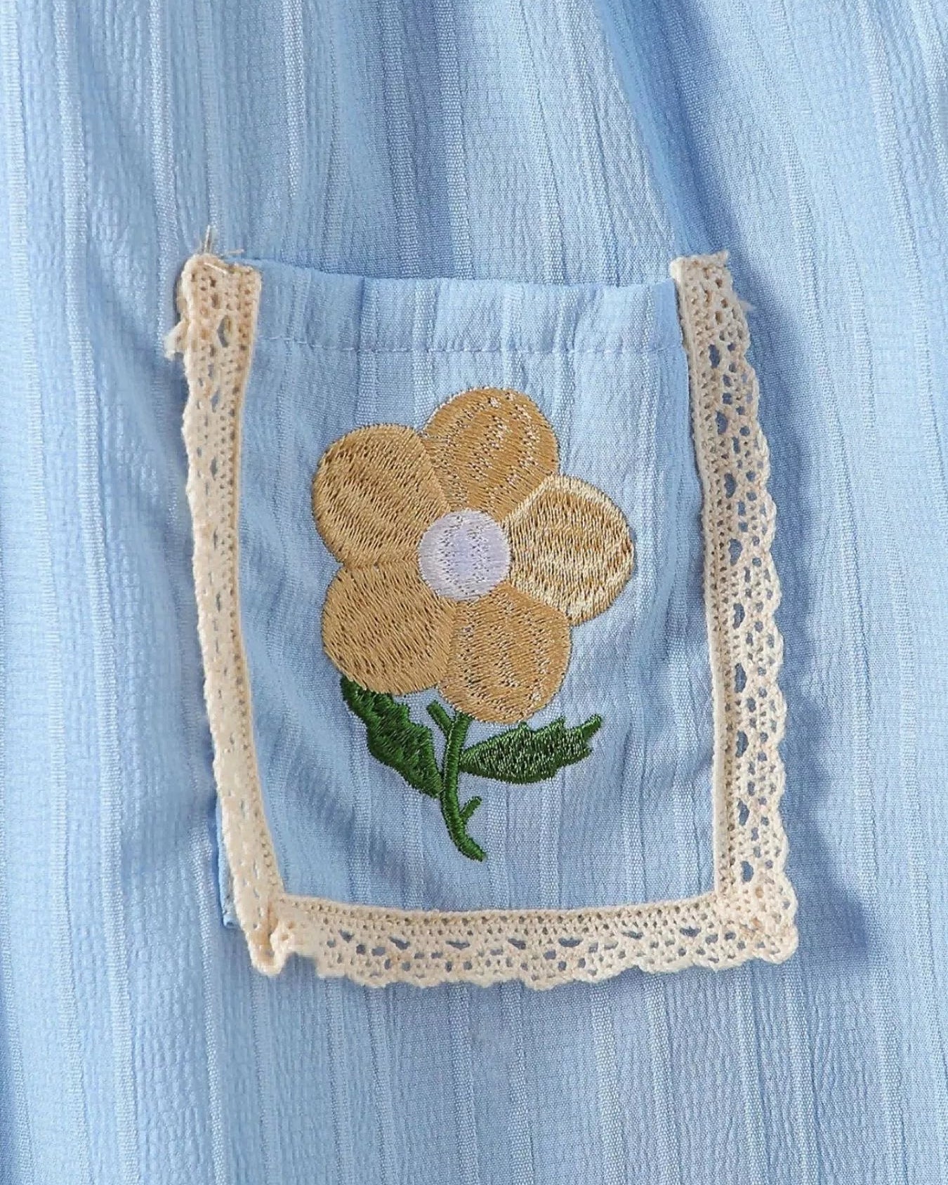 Sky blue kids dress pocket with golden flower embroidery and cream lace edging, pocket close-up
