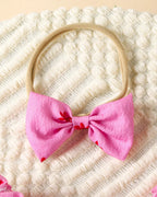 Hot pink baby floral bow headband with beige stretch band, close-up view
