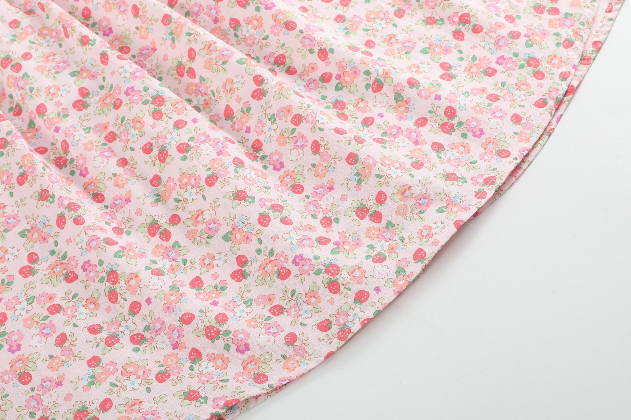Pink kids dress with strawberry and multicolor floral print, fabric close-up