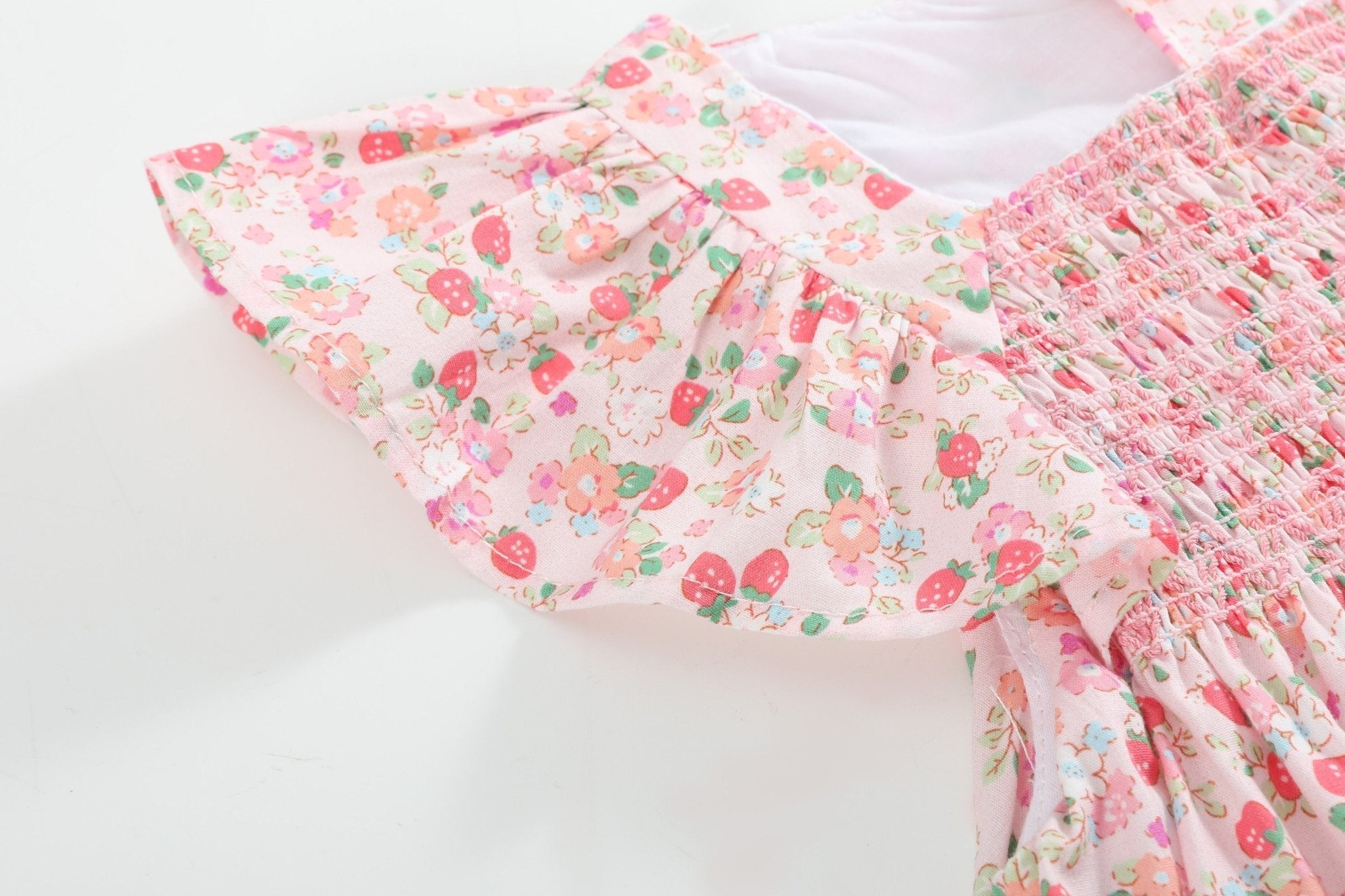 Pink strawberry floral kids dress with smocked bodice and layered flutter sleeve, close-up view