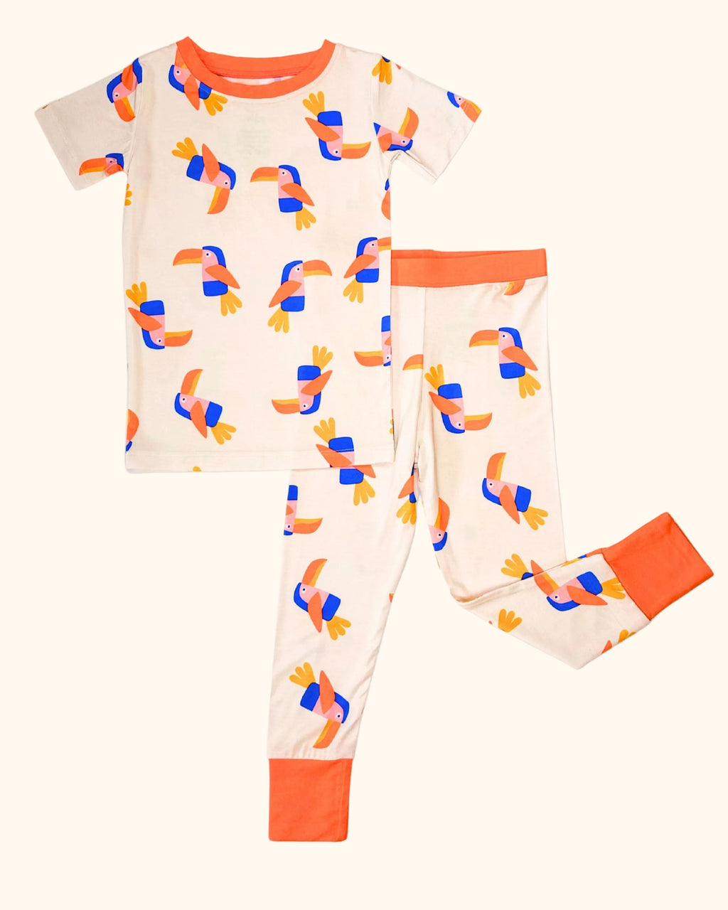 Cream kids toucan bamboo pajama set with colorful bird print and orange trim, front flat-lay view