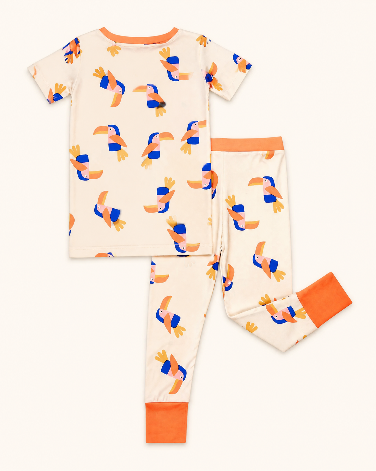 Cream kids toucan bamboo pajama set with orange waistband and ankle cuffs, back flat-lay view