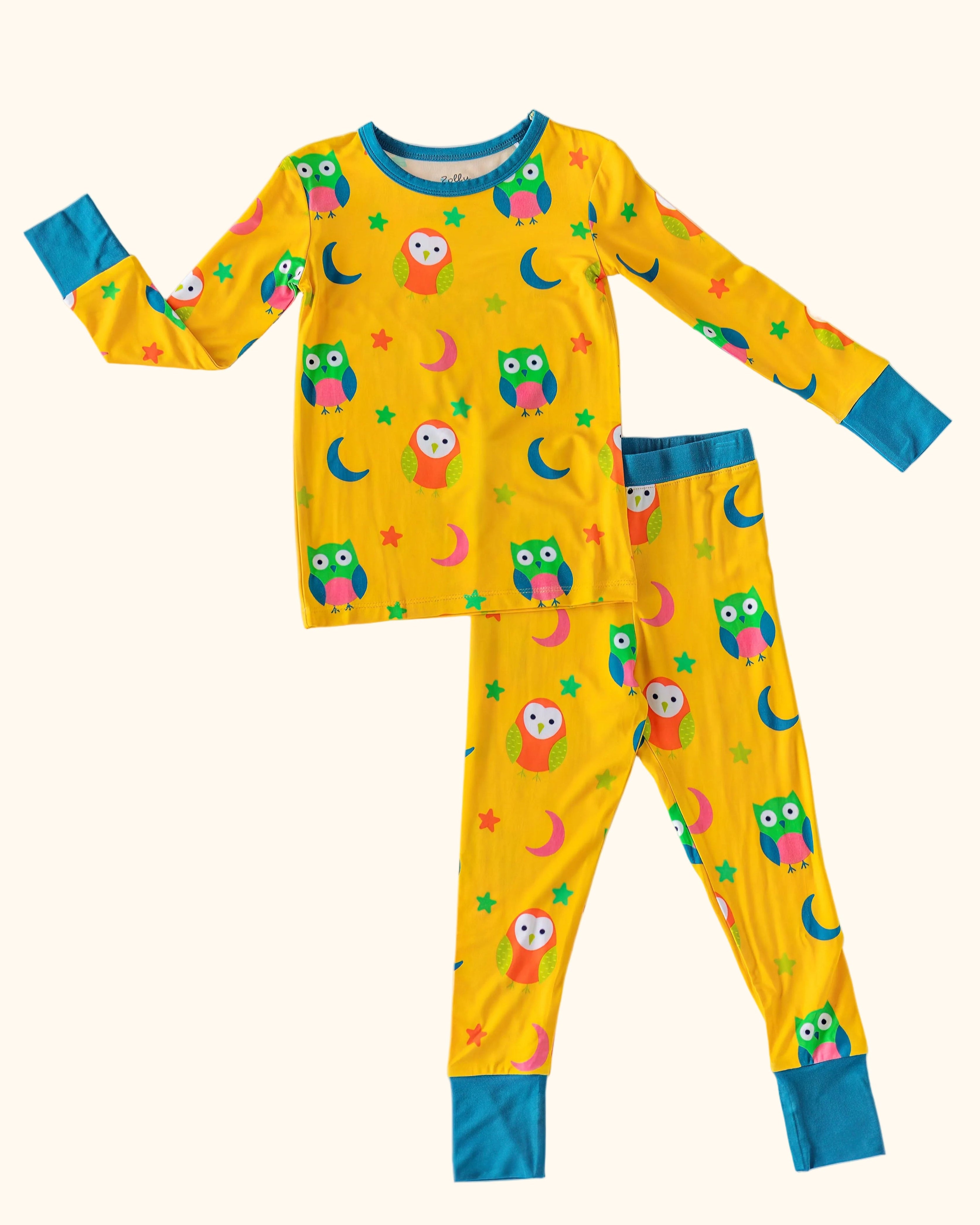 Yellow kids owl print bamboo pajama set with teal cuffs and colorful moons and stars, front flat-lay view