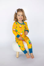 Yellow kids owl print long-sleeve pajama set with teal cuffs, modeled front view
