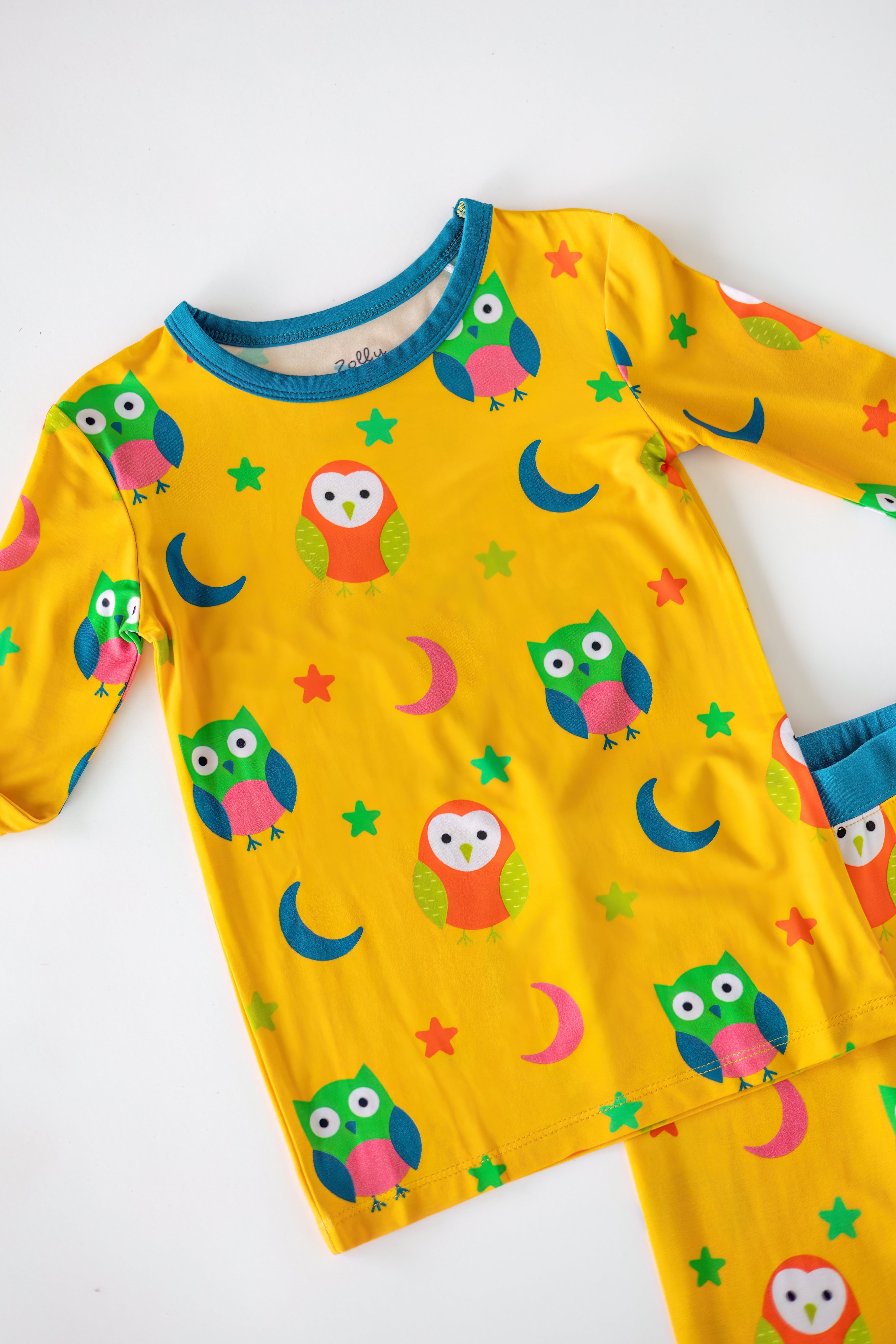 Yellow kids bamboo pajama set with colorful owls moons and stars, top detail view