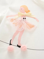 White kids T-shirt with ballet dancer, pink tulle tutu, cream bow and pom-poms, design close-up