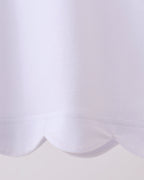 White kids top with rounded scalloped bottom hem, close-up detail view