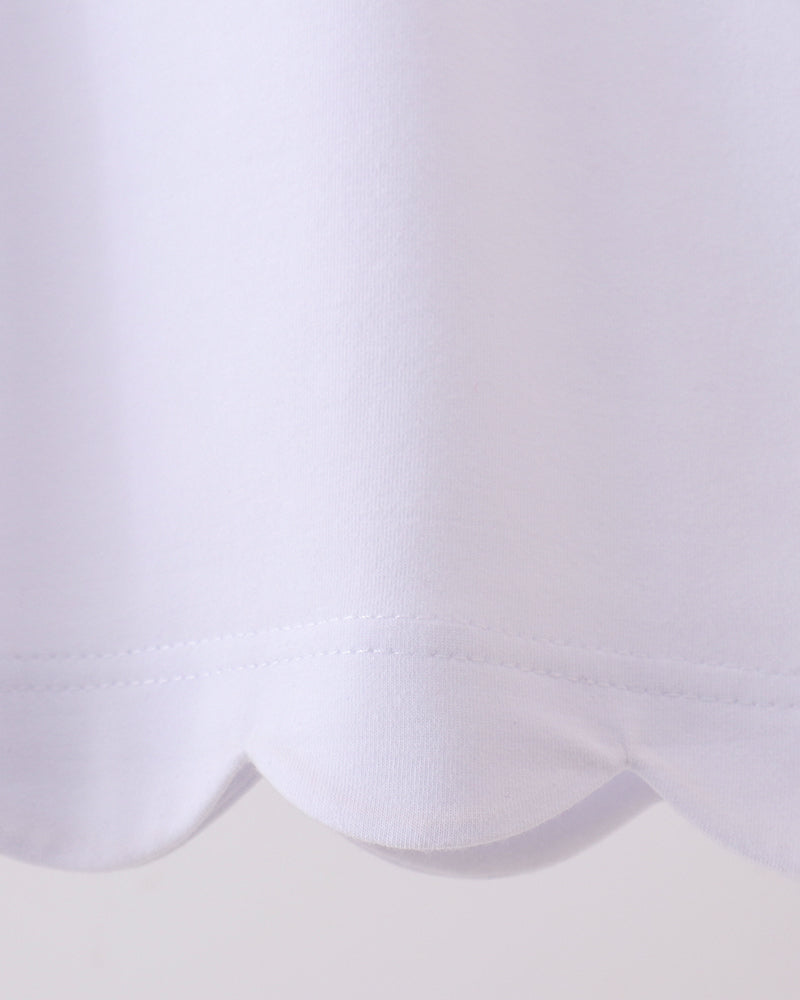White kids top with rounded scalloped bottom hem, close-up detail view