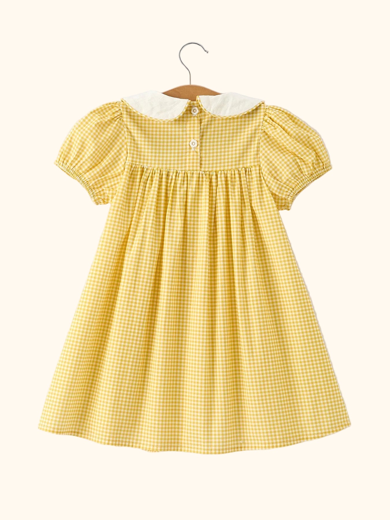 Yellow gingham kids dress with embroidered geese and smocked chest panel, close-up detail