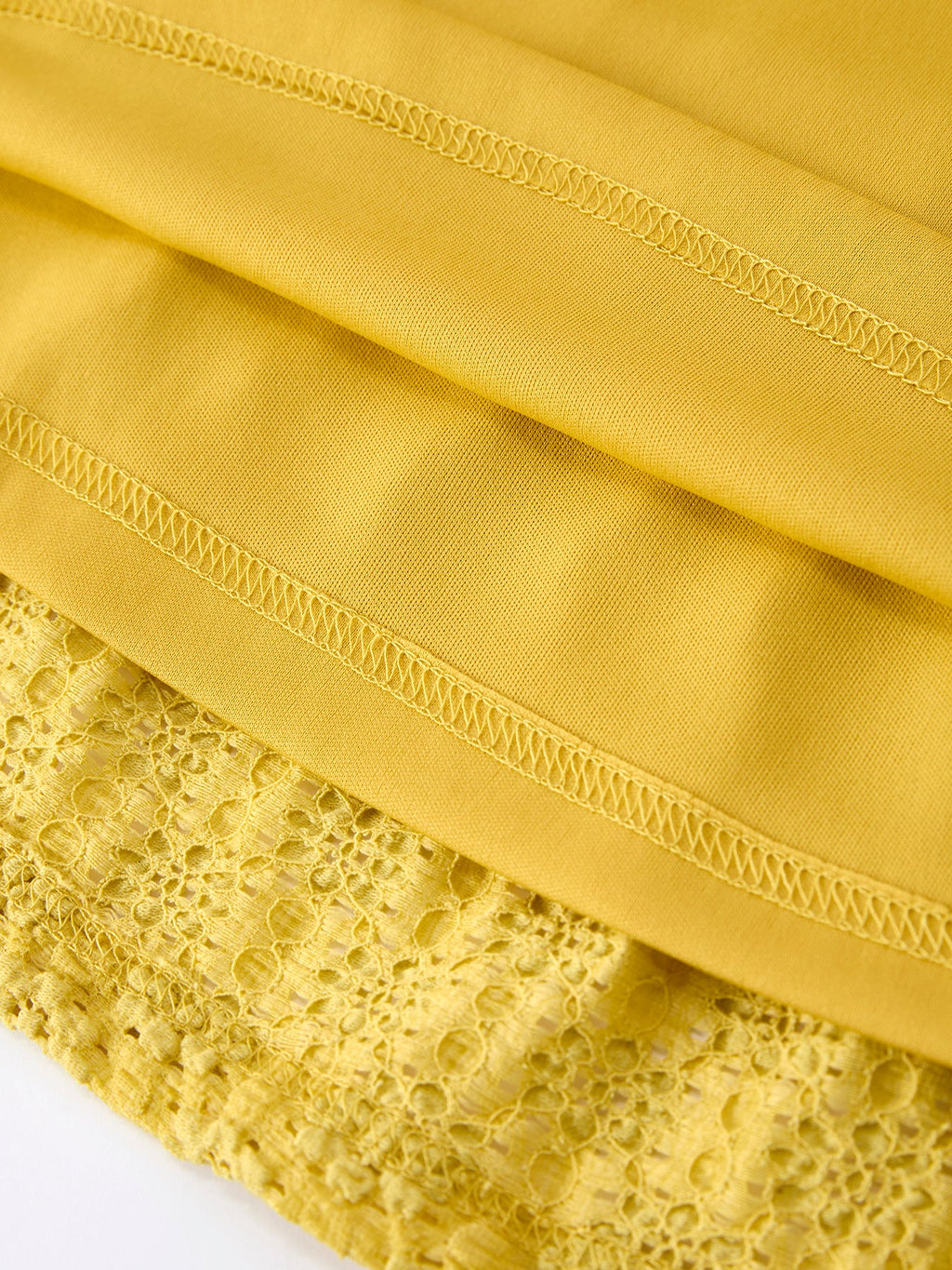 Yellow kids lace dress with smooth inner lining beneath openwork lace, hem detail view