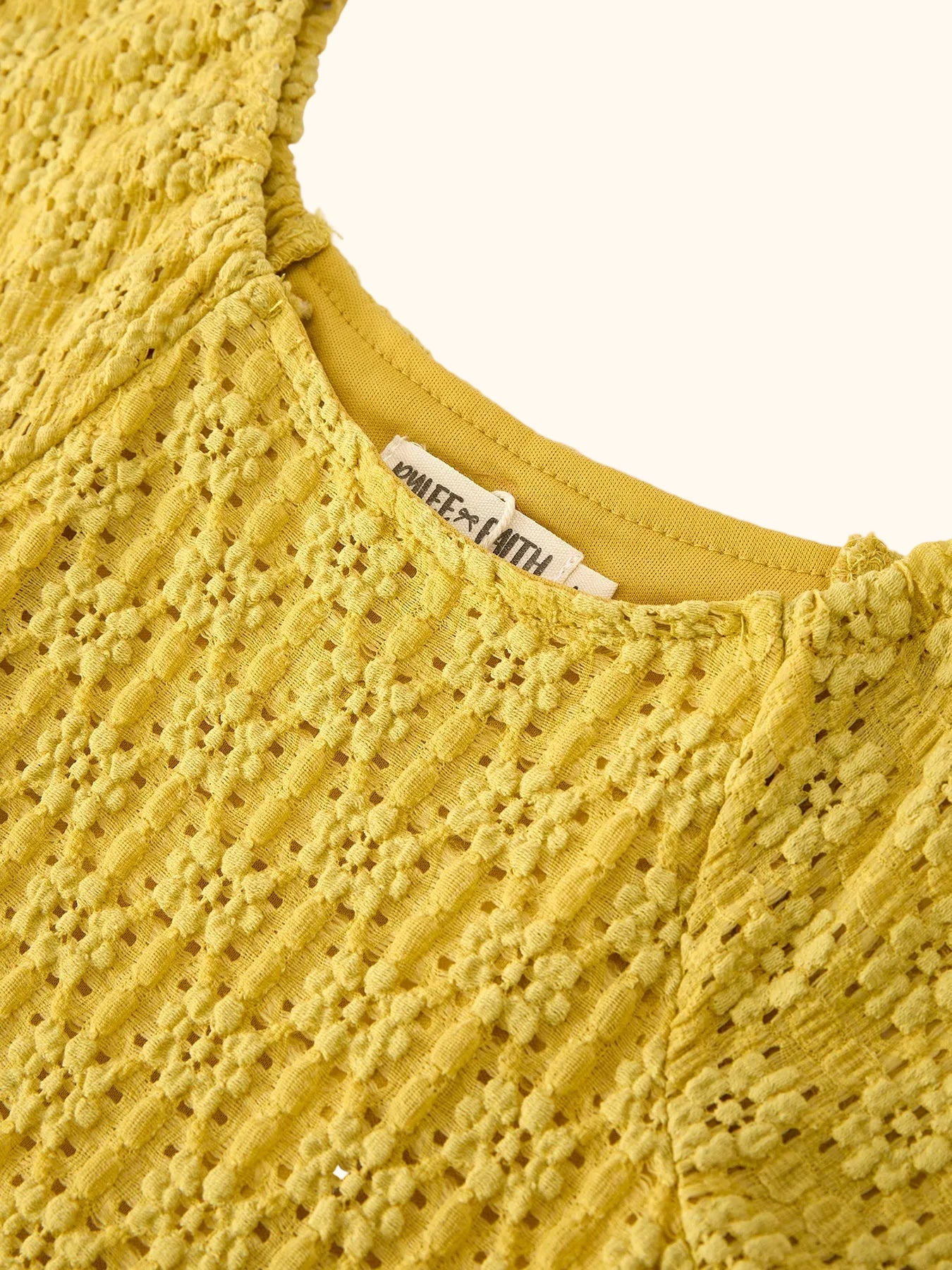 Yellow kids lace dress with round neckline and textured openwork lace, neckline close-up