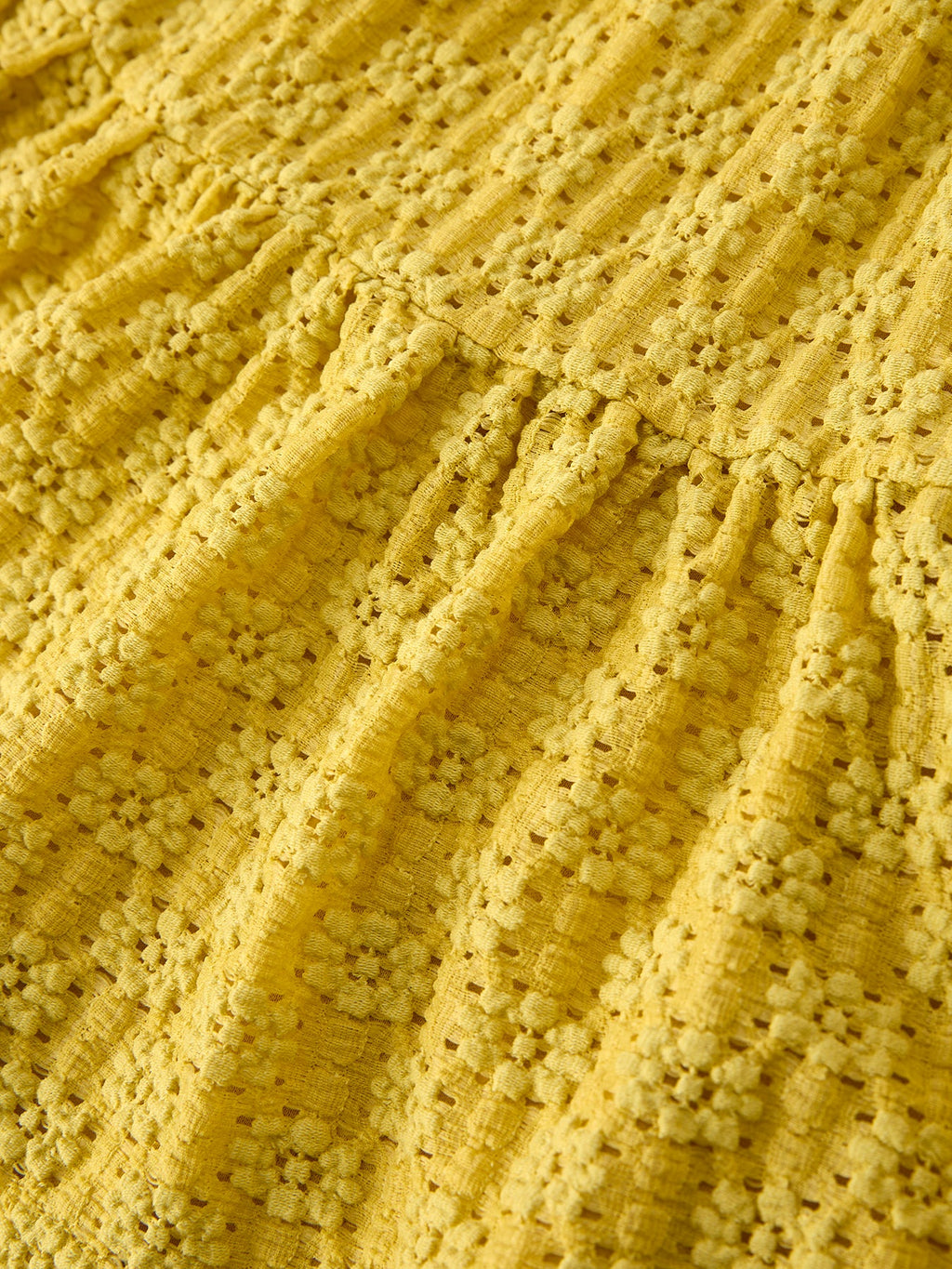 Yellow kids lace tiered dress with gathered waist and textured openwork fabric, seam close-up