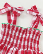 Red and white gingham tiered dress with bow tie straps and smocked bodice, close-up view